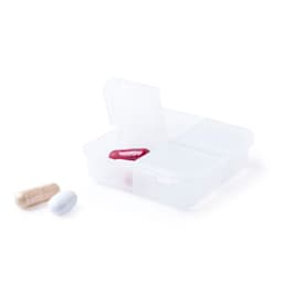 A clear pill organiser with four compartments, containing a red capsule, a white capsule, and a beige capsule.