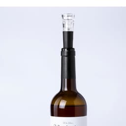 A drink bottle with a sleek black vacuum bottle stopper, topped with a clear glass section, showcasing an elegant design.