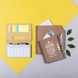 A brown notepad with a spiral binding, a sticky note holder with colourful notes, and a folder, set against a yellow background.