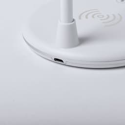 A white multifunction lamp with a circular base and a USB port, featuring wireless charging symbols on the surface.