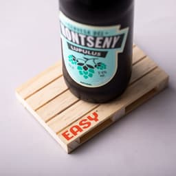 A drink bottle sits on a light wooden coaster with slats, featuring a logo. The coaster is rectangular in shape.