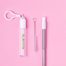 A drink bottle kit featuring a clear plastic case, a stainless steel straw, and a cleaning brush, all on a pink background.
