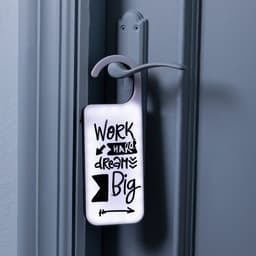 A decorative door hanger in white with black text and designs, featuring motivational phrases and a hook for hanging.