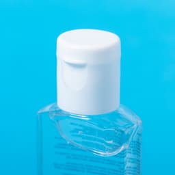 A clear hand sanitiser with a white cap against a blue background, featuring a branding label.