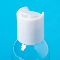 A clear hand sanitiser bottle with a white flip-top cap against a blue background.