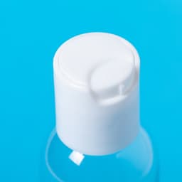 A clear hand sanitiser bottle with a white pump cap on a blue background.