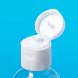 A clear hand sanitiser bottle with a white flip-top lid against a bright blue background.