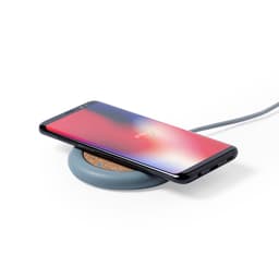 A wireless charger in grey with a cork surface, featuring a smartphone placed on top of it.