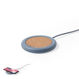 A wireless charger with a grey silicone base and a cork charging surface, accompanied by a smartphone on the side.