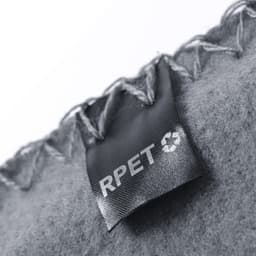 A grey blanket with stitching detail and a tag indicating it’s made from recycled materials.