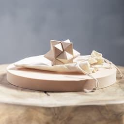 A wooden puzzle game in natural tones, displayed on a circular wooden base and accompanied by a cotton drawstring bag.
