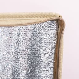 A cooler bag featuring a silver insulated lining and a tan exterior with a zip closure.