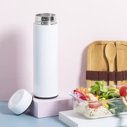 A drink bottle in white with a stainless steel lid, next to a food container and wooden utensils on a pastel background.