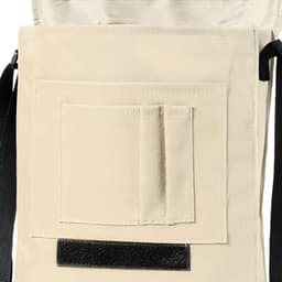 A beige Milán Bag featuring a front pocket and a flap closure, with a black strap and logo branding.