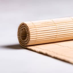A rolled bamboo place mat in a natural finish, featuring a simple woven design. It has a branding logo.