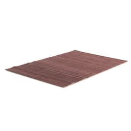 A decorative rug in shades of brown, featuring a textured surface and a simple design. It has a brand logo.