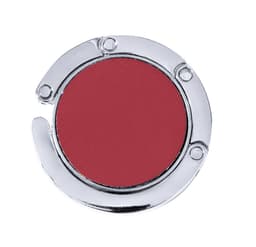 A round, foldable bag hanger in shiny silver and deep red, featuring a simple design and a logo.