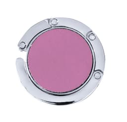 A foldable bag hanger in silver with a round pink surface. It has a sleek, metallic design.