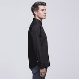 A side view of a black button-up shirt, featuring a collar and long sleeves, modelled by a man.