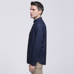A navy blue button-up shirt with a collar, displayed on a model facing sideways. The shirt has a logo.