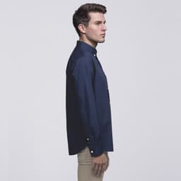 A navy button-up shirt displayed on a model from the side, featuring a collar and a logo.