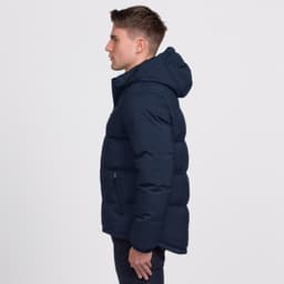 A man wearing a navy blue puffer jacket with a hood, featuring a zippered pocket on the side.