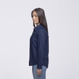 A side view of a woman wearing a navy button-up shirt, featuring a logo on the sleeve.