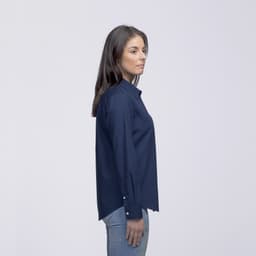 A side view of a woman wearing a navy button-up shirt with long sleeves and a collar. The shirt has a logo.