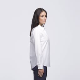 A white button-up shirt on a woman, featuring a simple design and a logo on the shirt.