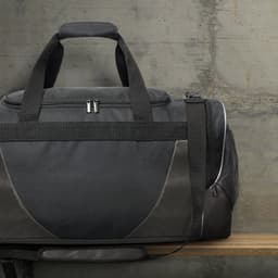 A black duffle bag with grey accents and a logo, featuring handles and a zipper closure, resting on a wooden surface.