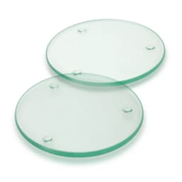 A set of two round glass coasters, transparent with a slight green tint and raised dots on the underside.