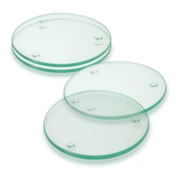 A set of four round glass coasters in a light green hue, featuring raised dots for grip.