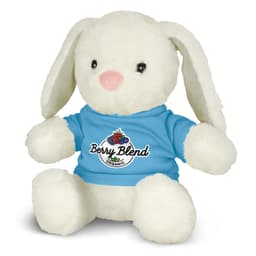 A soft, white plush toy rabbit wearing a blue shirt with a logo. It has long ears and a pink nose.