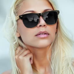Sunglasses featuring black lenses with a bamboo frame, displayed on a model with long, light blonde hair.