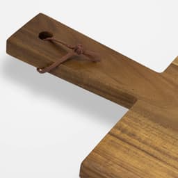 A wooden chopping board with a natural finish and a leather tie attached for hanging.