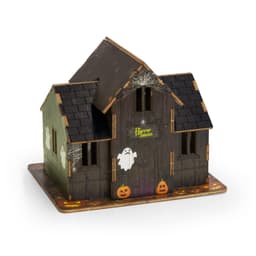 A wooden model of a spooky house in dark colours, featuring ghosts and pumpkins, with a logo on the front.