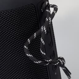 A black Bluetooth speaker with textured surface and a decorative cord attached.