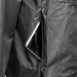 A close-up view of a black windbreaker jacket featuring a zippered pocket with a smartphone inside.