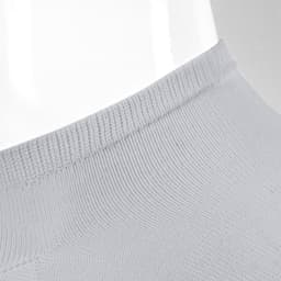 A pair of grey ankle socks displayed on a mannequin. The socks feature a ribbed design and a branding logo.