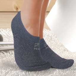 Ankle socks in dark grey, featuring a logo, displayed on a person's feet on a textured surface.