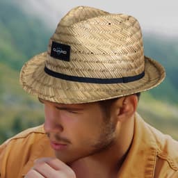 A straw fedora hat in natural tones with a black band and logo, worn by a man outdoors.