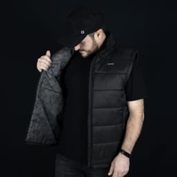 A man in a black Swiss Peak Urban Puffer Vest, holding it open to display the interior lining.