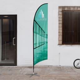 A medium feather flag kit with a teal design, featuring a logo, set up outdoors.
