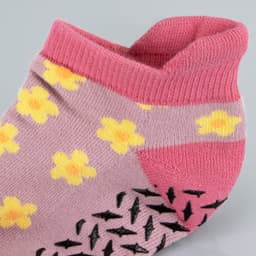 A pair of pink ankle grip socks with yellow flower designs and a textured sole for added grip.