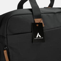 A black duffle bag with a leather tag and a logo, featuring sturdy handles and a sleek design.
