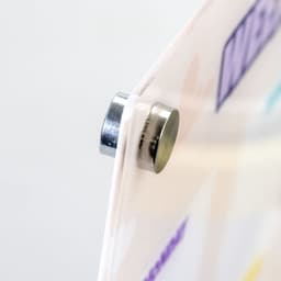 A magnetic fastener holding a clear, colourful planner, with various pastel shades visible on the surface.