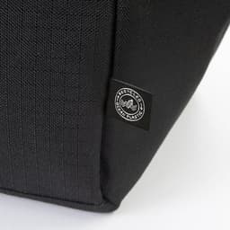 A black cooler bag featuring a logo, made from recycled materials. The textured fabric is visible in the image.