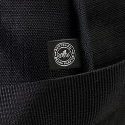 A black duffle bag made from recycled ocean plastic, featuring a small logo tag.