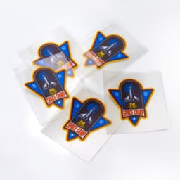 A set of colourful stickers featuring a rocket design and "Space Camp" text, presented on transparent backing.