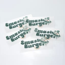 A collection of green and white stickers featuring a playful logo and branding for "Smash Burger."